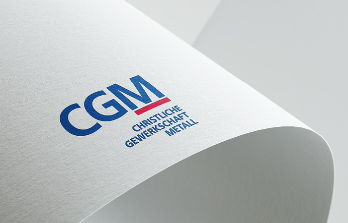 Logo CGM, plastisch dargestellt auf einem gebogenen Blatt Papier