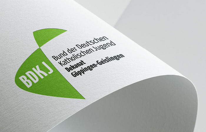 Logo BDKJ, plastisch dargestellt auf einem gebogenen Blatt Papier