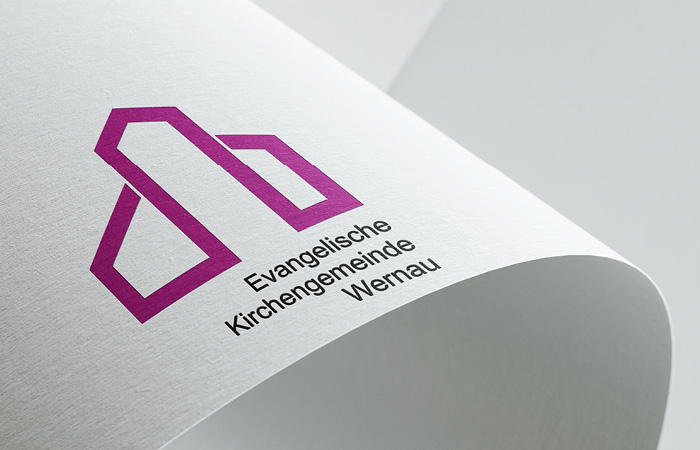 Logo Evangelische Kirchengemeinde Wernau, plastisch dargestellt auf einem gebogenen Blatt Papier
