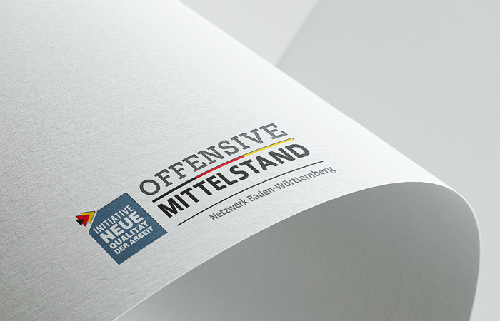 Logo Offensive Mittelstand, plastisch dargestellt auf einem gebogenen Blatt Papier
