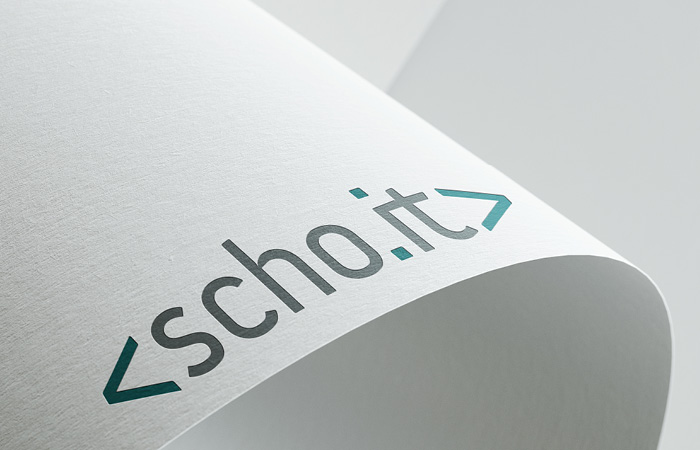 Logo Scho IT, plastisch dargestellt auf einem gebogenen Blatt Papier