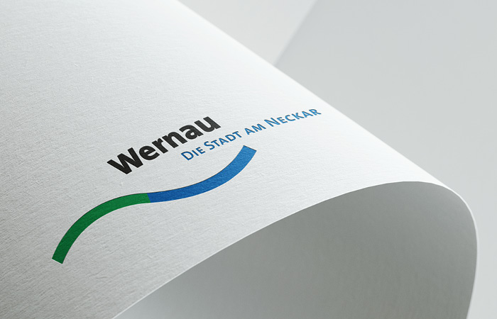 Logo Wernau, plastisch dargestellt auf einem gebogenen Blatt Papier